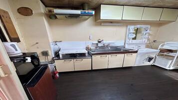 A kitchen with a microwave, stove, and sink. There is a fire extinguisher on the floor.