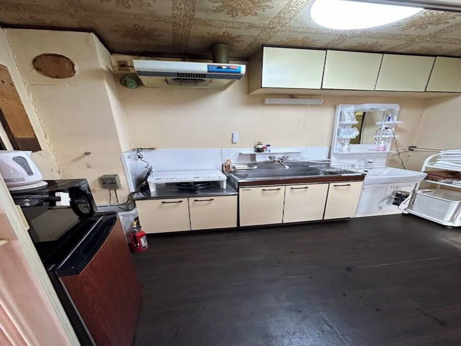 A kitchen with a microwave, stove, and sink. There is a fire extinguisher on the floor.
