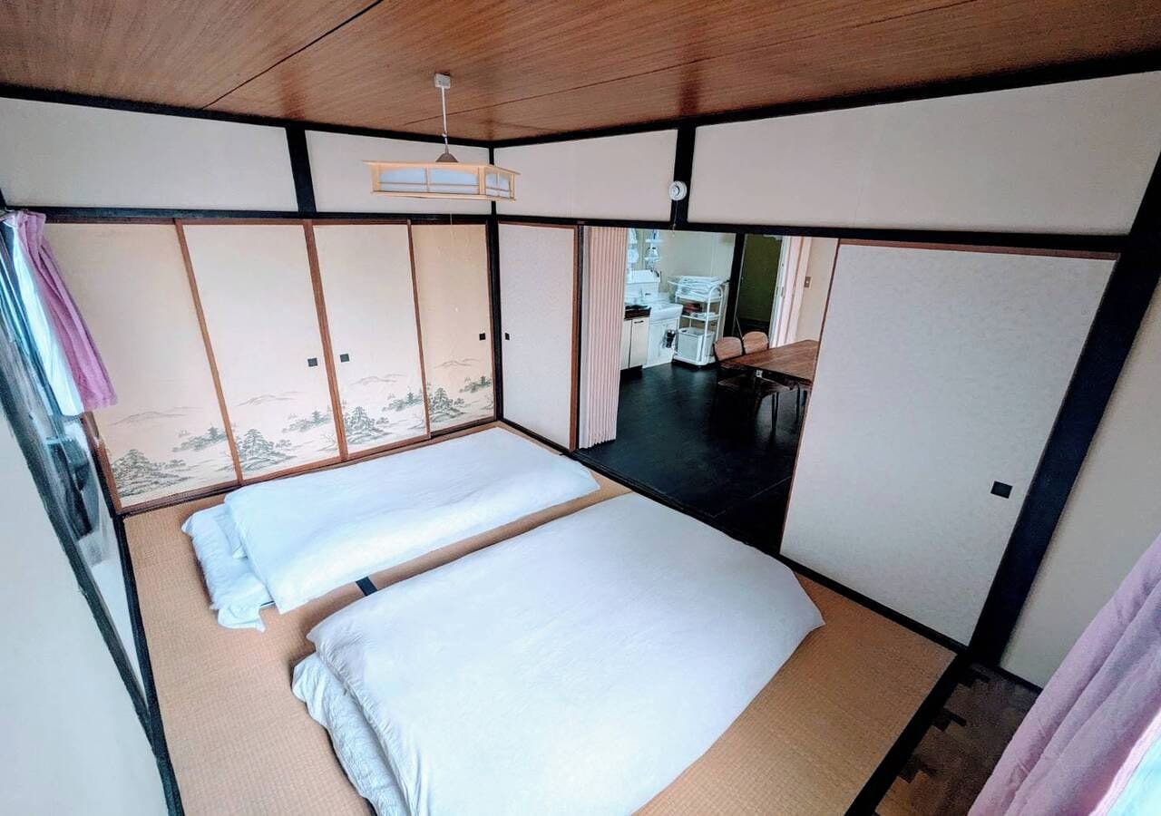 Een traditionele Japanse kamer met tatami vloerbedekking, een laag plafond en schuifdeuren.