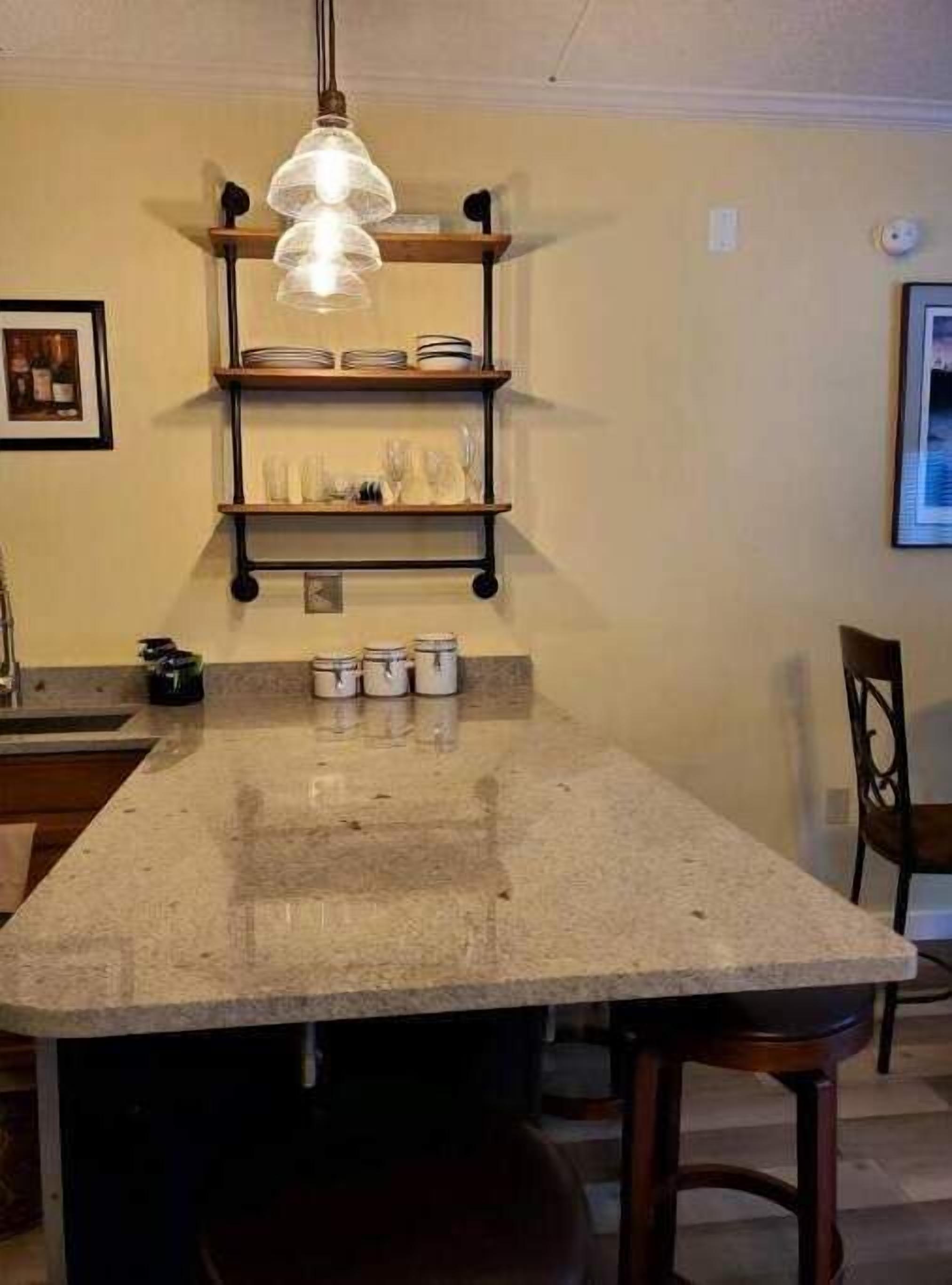 A kitchen with a central island, pendant lighting, and built-in shelves.