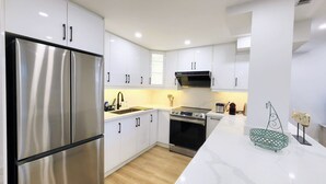 A modern kitchen with white cabinetry, stainless steel appliances, and a marble countertop. - Serene High-celling Retreat in Upsacle and Safe Neighbourhood (Oakville)