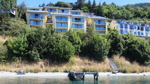A coastal hotel with multiple-story buildings, a dock, and a staircase leading up to the buildings. - Lakeside Landing - lakefront and walk to town (Queenstown)