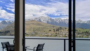 A view from a balcony with two chairs, overlooking a lake and a town with mountains in the background. - Lakeside Landing - lakefront and walk to town (Queenstown)