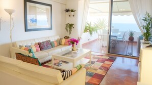 A living room with a sofa, coffee table, and a view of the outdoors through a sliding glass door. - Marazul DEL SUR Face A LA MER (ADEJE)