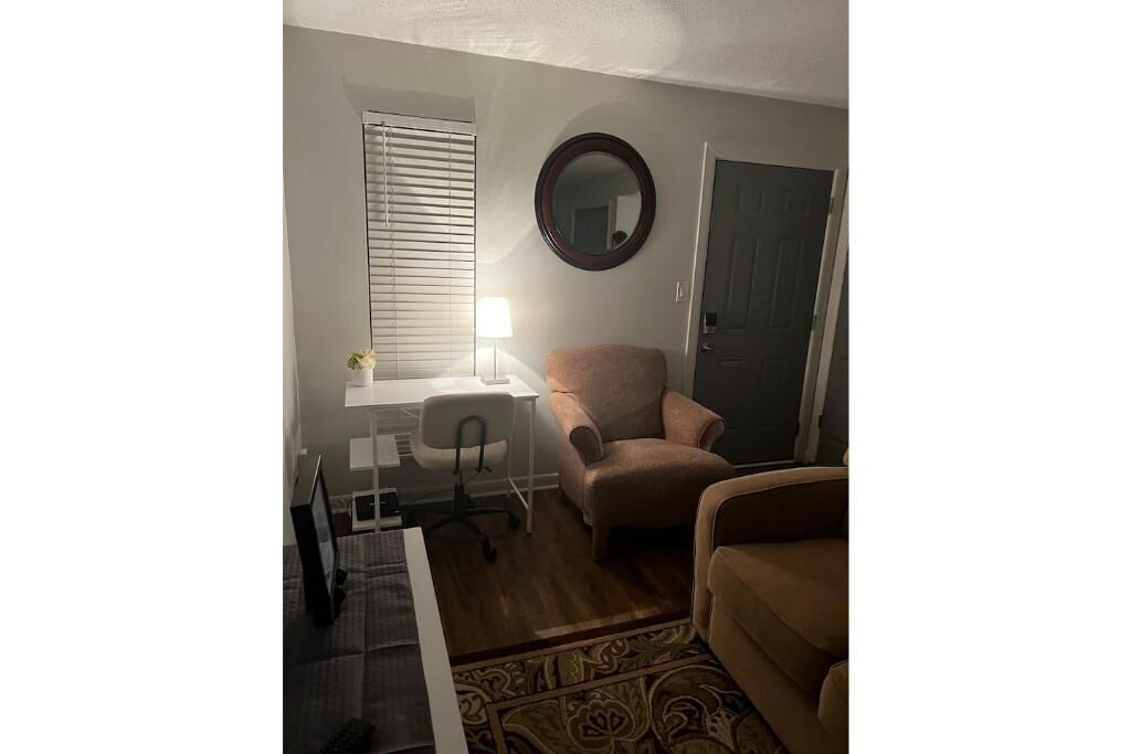 A small, well-lit room with a desk, chair, and two sofas.