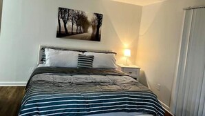 Une chambre à coucher avec un lit, une table de chevet, une lampe et un tableau au mur.