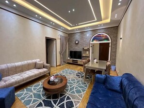 Relax in this stylish living room with a beige sofa, blue sofa, and geometric patterned rug.