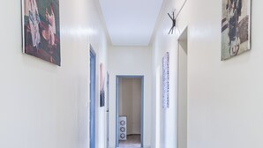 A hallway with white walls, black and white patterned floor tiles, and framed artwork on the walls. - Hôtel Mauritania Centre Tangier (Tangier)