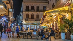 A bustling street scene with outdoor seating at Cafe Central, surrounded by historic buildings with balconies and traditional architecture. - Hôtel Mauritania Centre Tangier (Tangier)