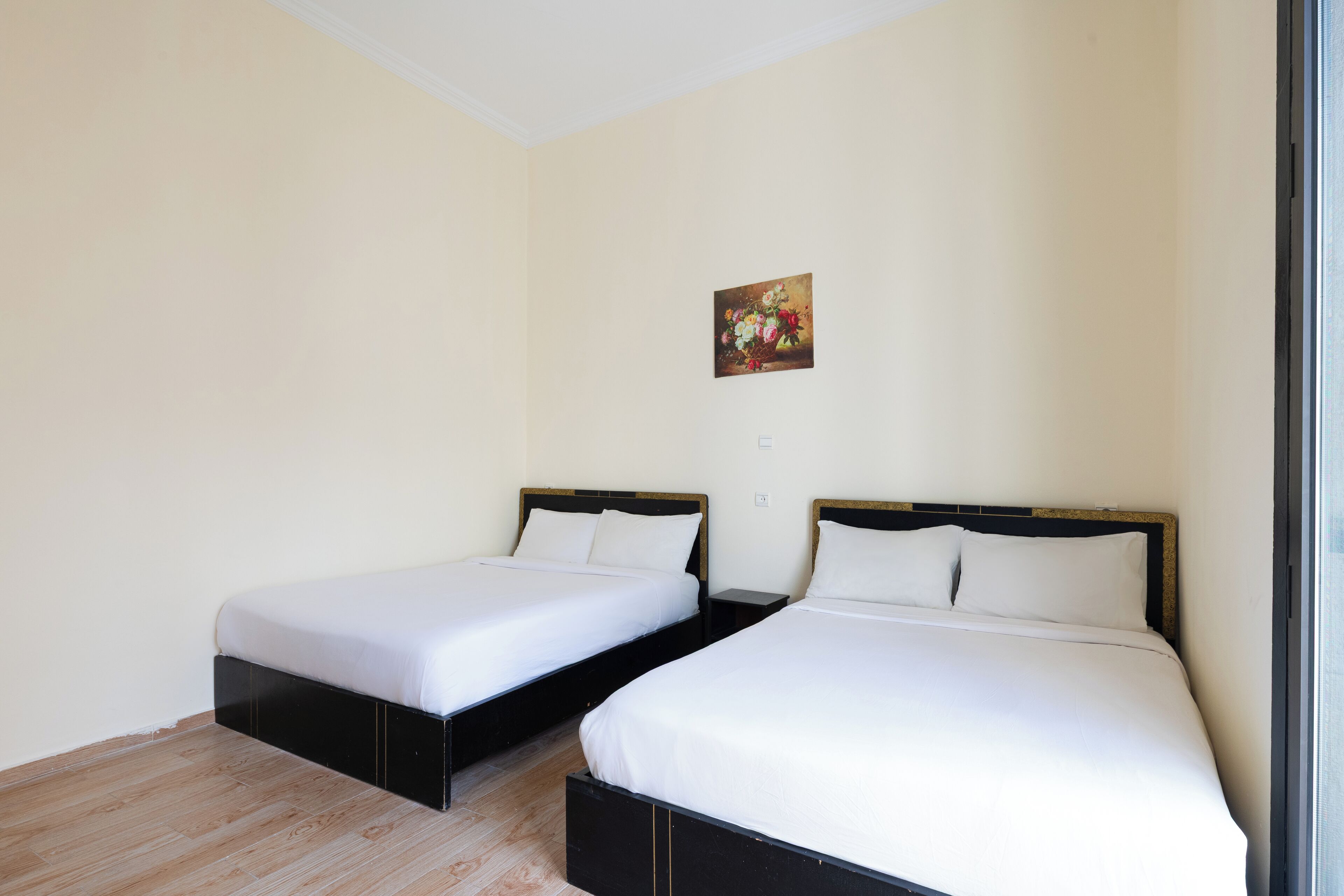Una habitación con dos camas individuales, cabeceros de madera, ropa de cama blanca y un cuadro en la pared.