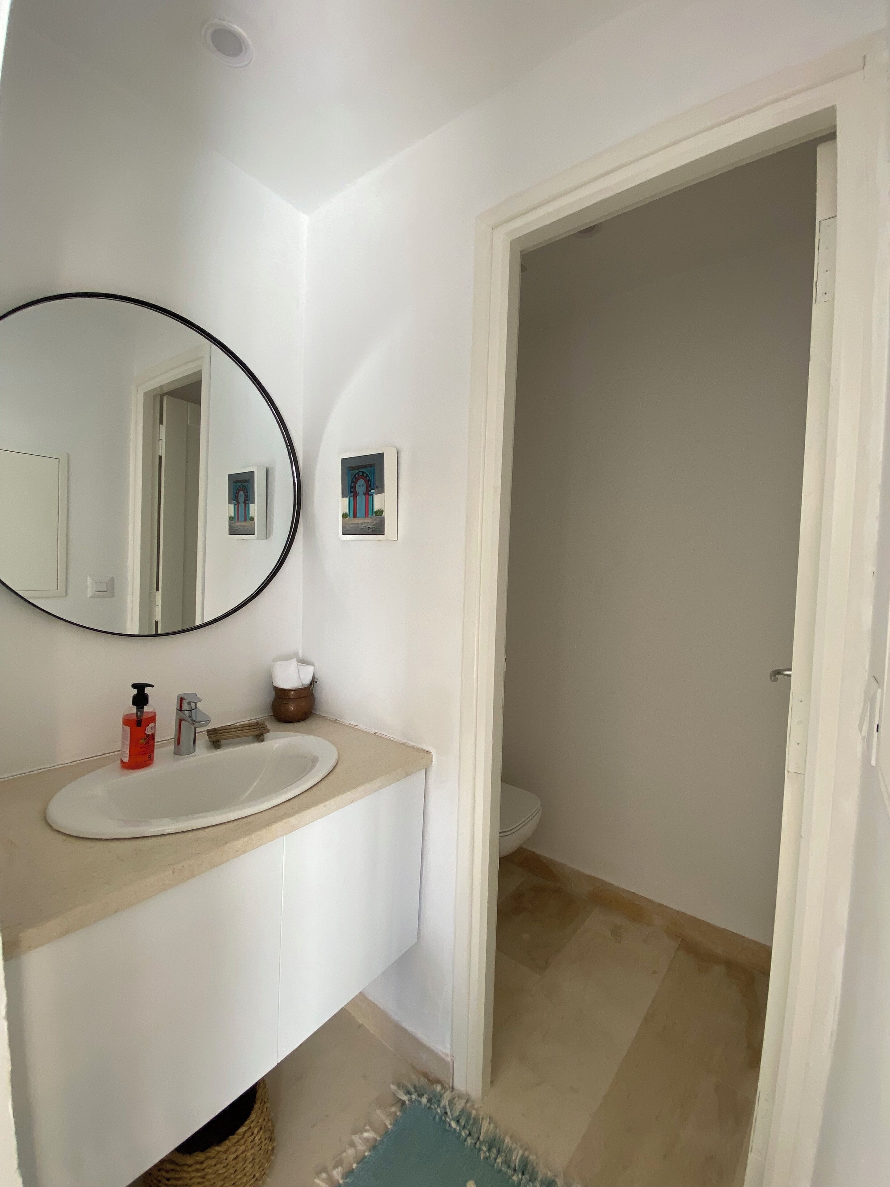 A bathroom with a white sink, a mirror, and a toilet.
