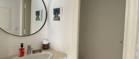 A bathroom with a white sink, a mirror, and a toilet.