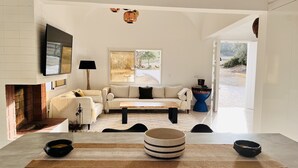 Un salon moderne avec une cheminée, un canapé, une table basse et un coin repas agrémenté d’un tapis et de quelques bols.