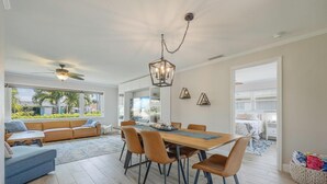 Un comedor amplio con una mesa y sillas de madera, un ventilador de techo y vistas al exterior.