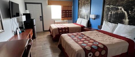 A hotel room with two beds, a desk, a coffee machine, and a large window.