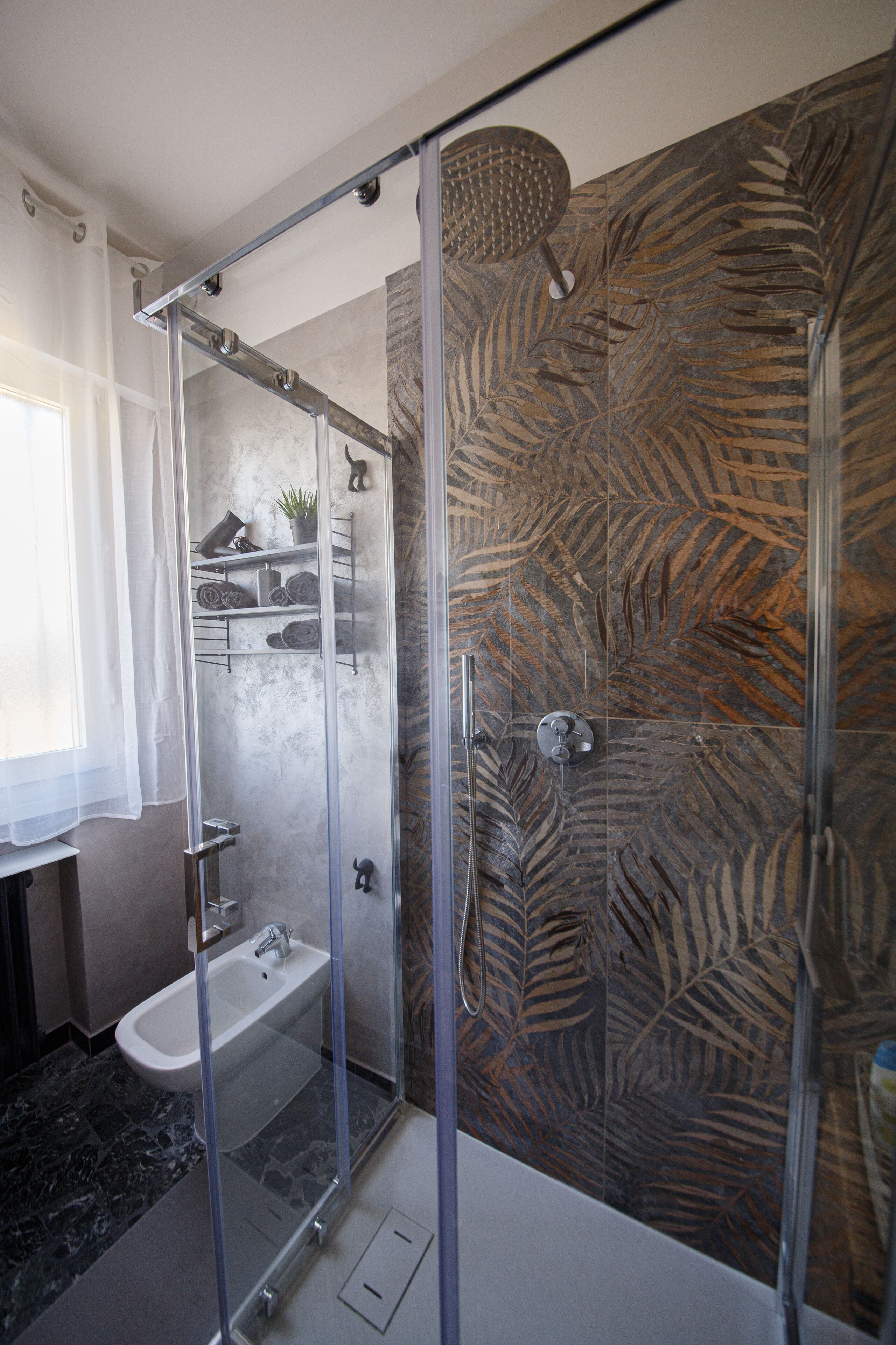 A modern bathroom with a glass-enclosed shower, a white bathtub, and a marble-patterned wall.