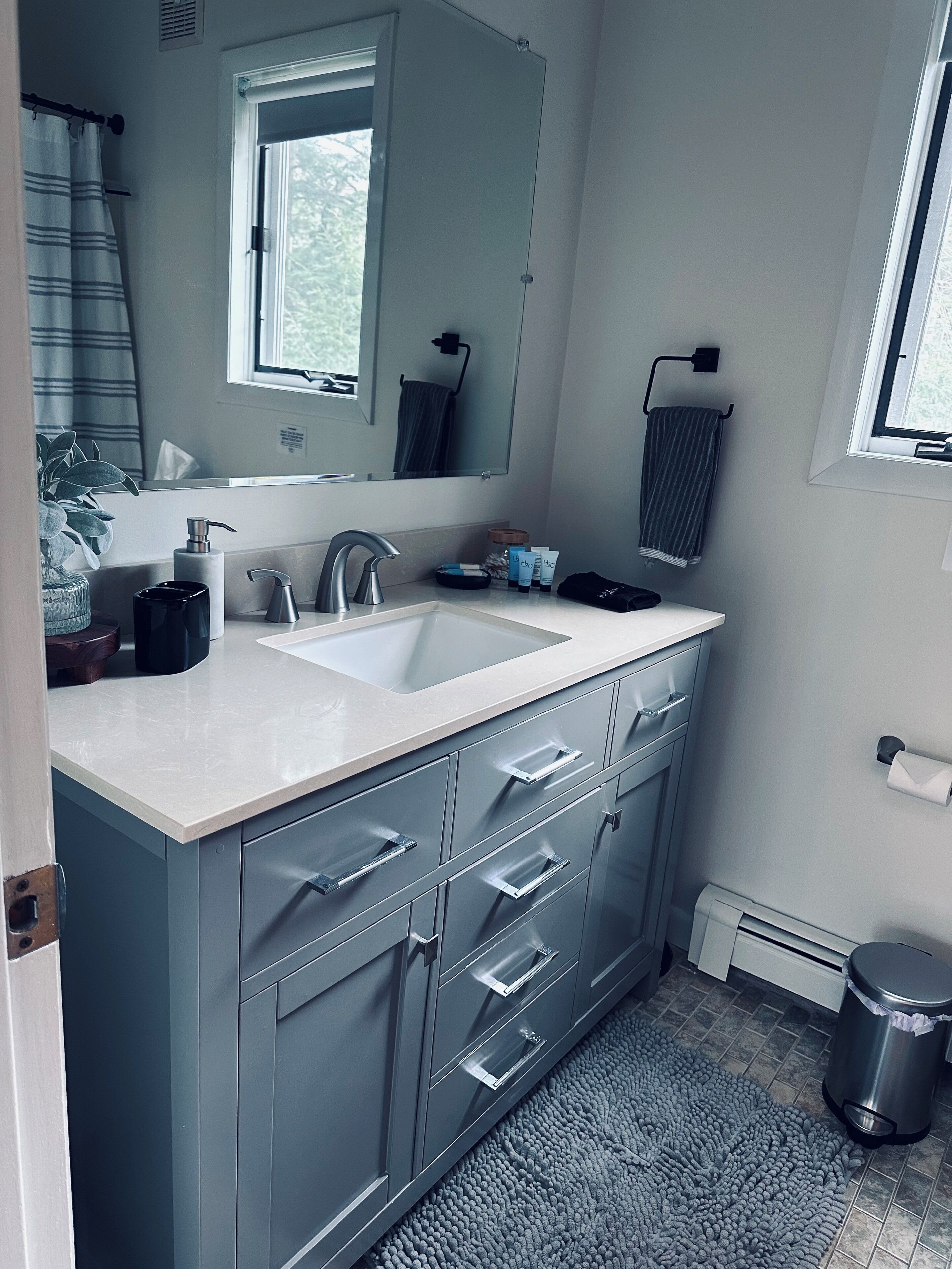 Ein modernes Badezimmer mit einem großen Waschbecken, einem Spiegel und integrierten Schränken.