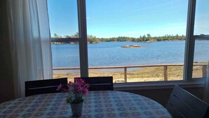 Una habitación con un ventanal grande que ofrece vistas a un lago y árboles a lo lejos.