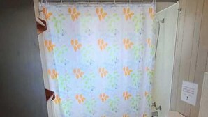 A bathroom with a toilet, sink, and shower curtain. - Cottage #7 - 2 Bedroom - Katawoda Cottages (Nobel)