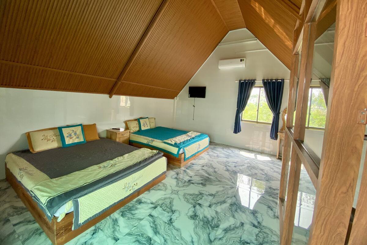 A room with two beds, a flat-screen TV, and a large window with curtains.