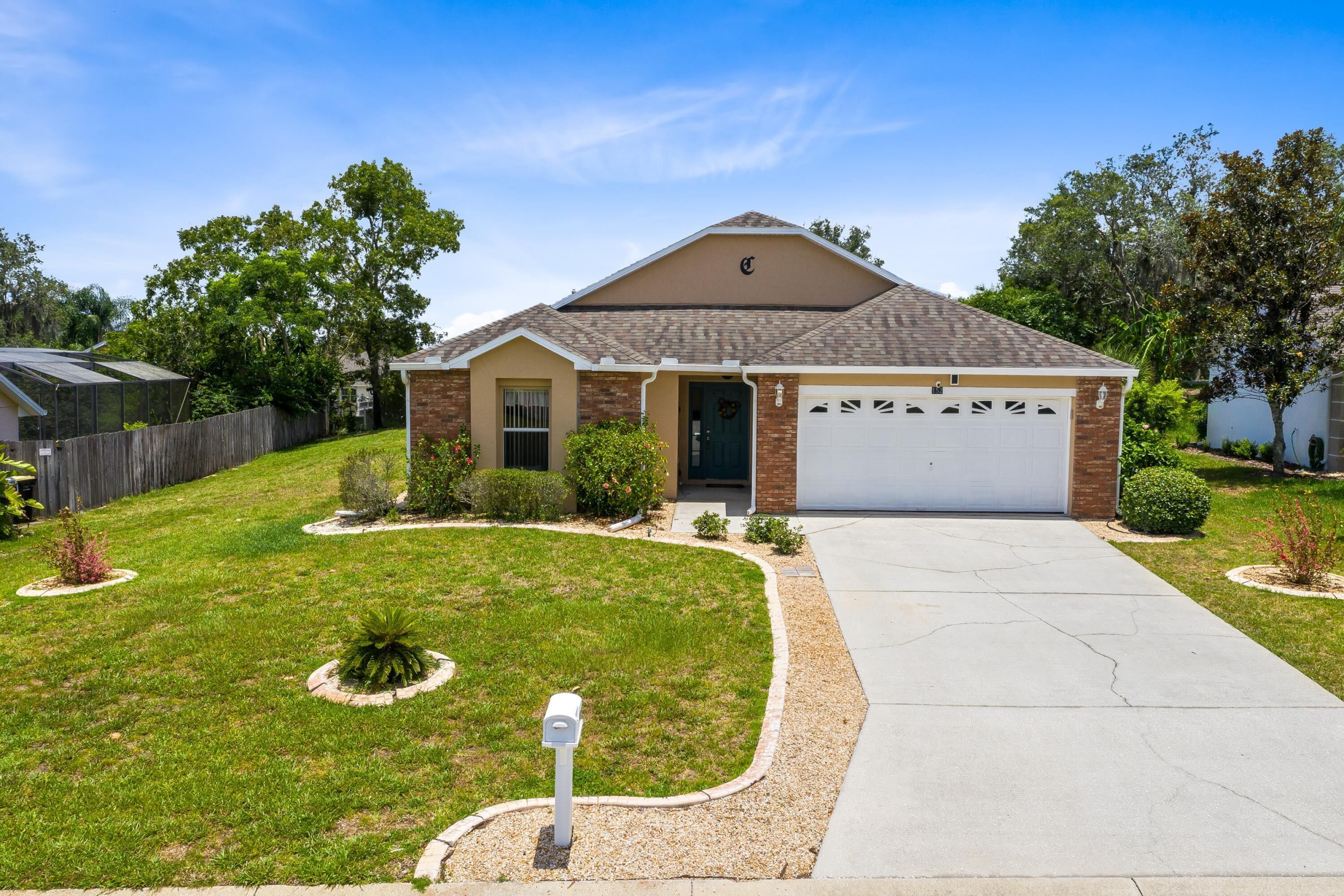 A single-story house with a garage, a front yard with a lawn and small plants, and a mailbox.