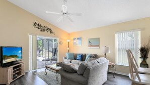 Ein Wohnzimmer mit Fernseher, Sofa und Deckenventilator.