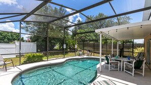 Ein überdachter Pool mit einer Terrasse, Stühlen und einem Tisch.