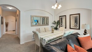 A living room with a dining table, a sofa, and a chandelier.