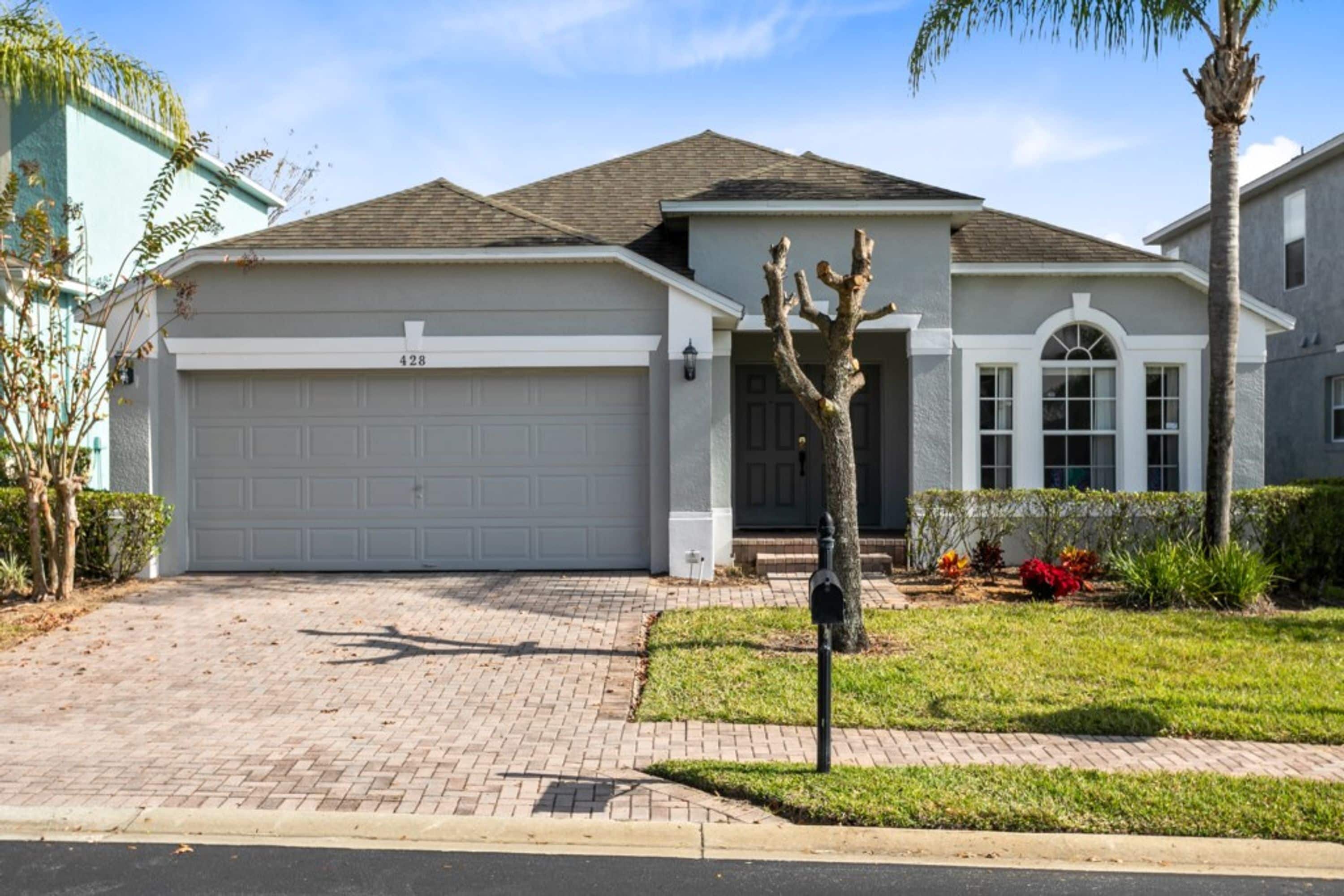 A residential house with a garage, a driveway, and a well-maintained lawn.