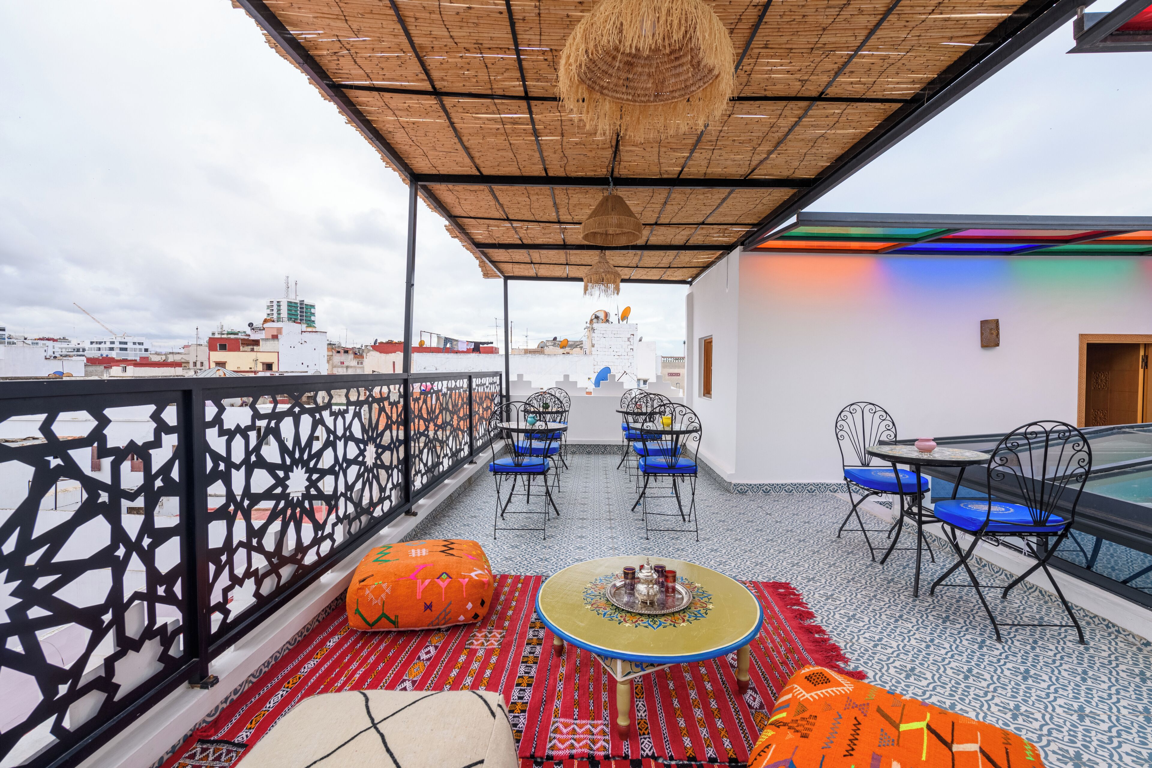 A rooftop terrace with a patterned floor, a round table with chairs, and a decorative hanging.