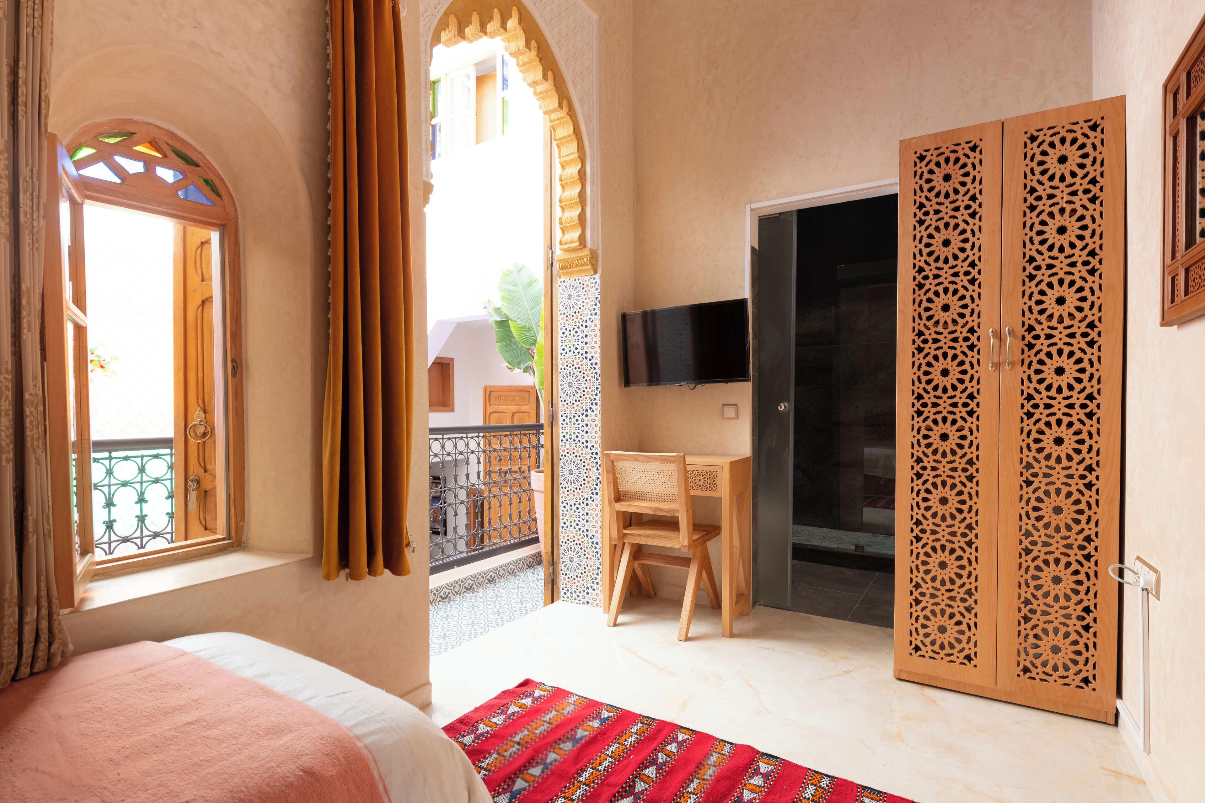 Una camera d'albergo con un letto, una scrivania, una televisione e un armadio.