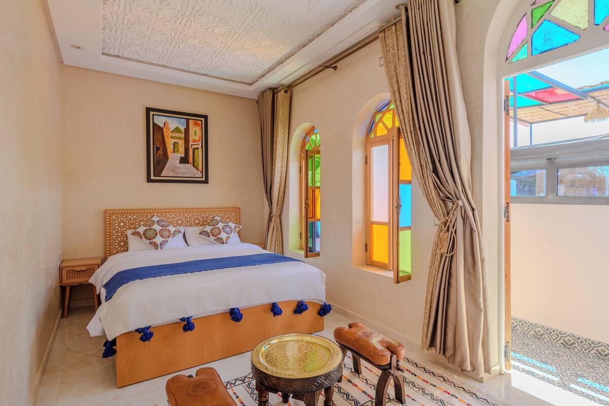 A bedroom with a large bed, a small round table, and a bench.