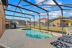 A covered outdoor swimming pool with a glass roof, surrounded by a patio area with lounge chairs. - Family Ready in Gated Community Near Attractions (Davenport)