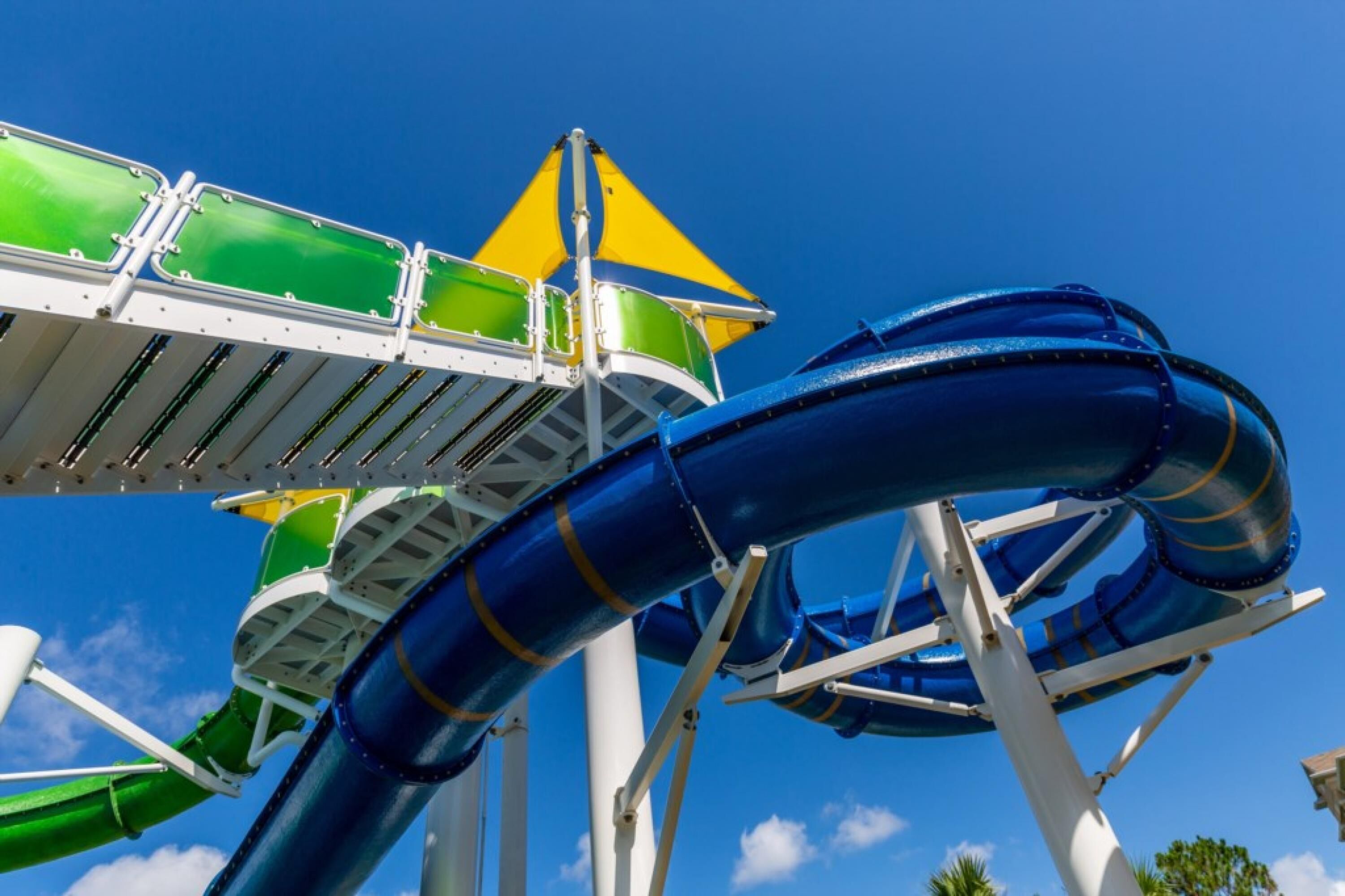 A water slide structure with multiple lanes and a green and yellow safety platform.