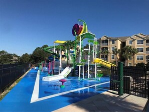 A water park with multiple slides and water features, surrounded by a fence and residential buildings in the background. - 3 BR 2 Miles to Disney Pool Free Wifi and More (Kissimmee)