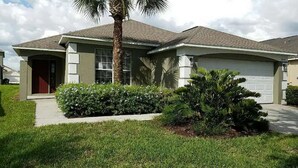 A two-story house with a front garage, a covered porch, and a well-maintained lawn. - 4 Bed 3 Bath in a Gated Community With Pool (Kissimmee)