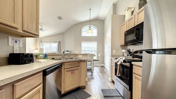 A spacious kitchen with wooden cabinets, stainless steel appliances, and a large island. - 4 Bed 3 Bath in a Gated Community With Pool (Kissimmee)