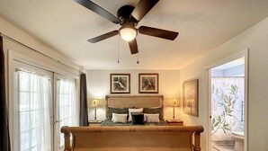 A bedroom with a large bed, ceiling fan, two bedside lamps, and framed artwork on the wall. - Lovely 3 bed Condo Near Disney Quiet Community (Kissimmee)