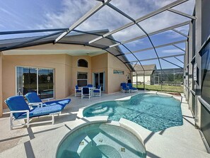 Ein überdachter Poolbereich im Freien mit blauen Liegestühlen und einer glasvergrößerten Terrasse.