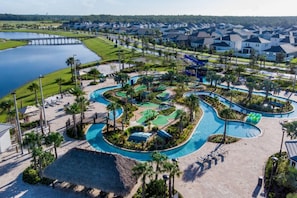 An aerial view of a resort with a central swimming pool, palm trees, and a dock extending into a lake. - 5 Bedroom Home is Ideal for an Elegant Vacation (Kissimmee)