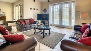 A spacious living room with a large TV, leather sofas, and a coffee table. - Fantastic 7 Bed 6 Bath in Prestigious Gated Comm (Kissimmee)