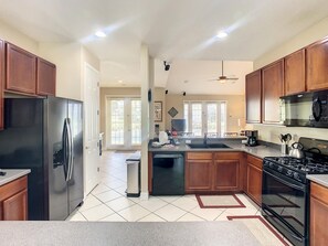 A modern kitchen with wooden cabinets, stainless steel appliances, and a large island. - Fantastic 7 Bed 6 Bath in Prestigious Gated Comm (Kissimmee)