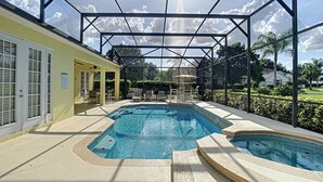A covered outdoor swimming pool with a sunshade structure, adjacent to a building with a door and windows. - Fantastic 7 Bed 6 Bath in Prestigious Gated Comm (Kissimmee)