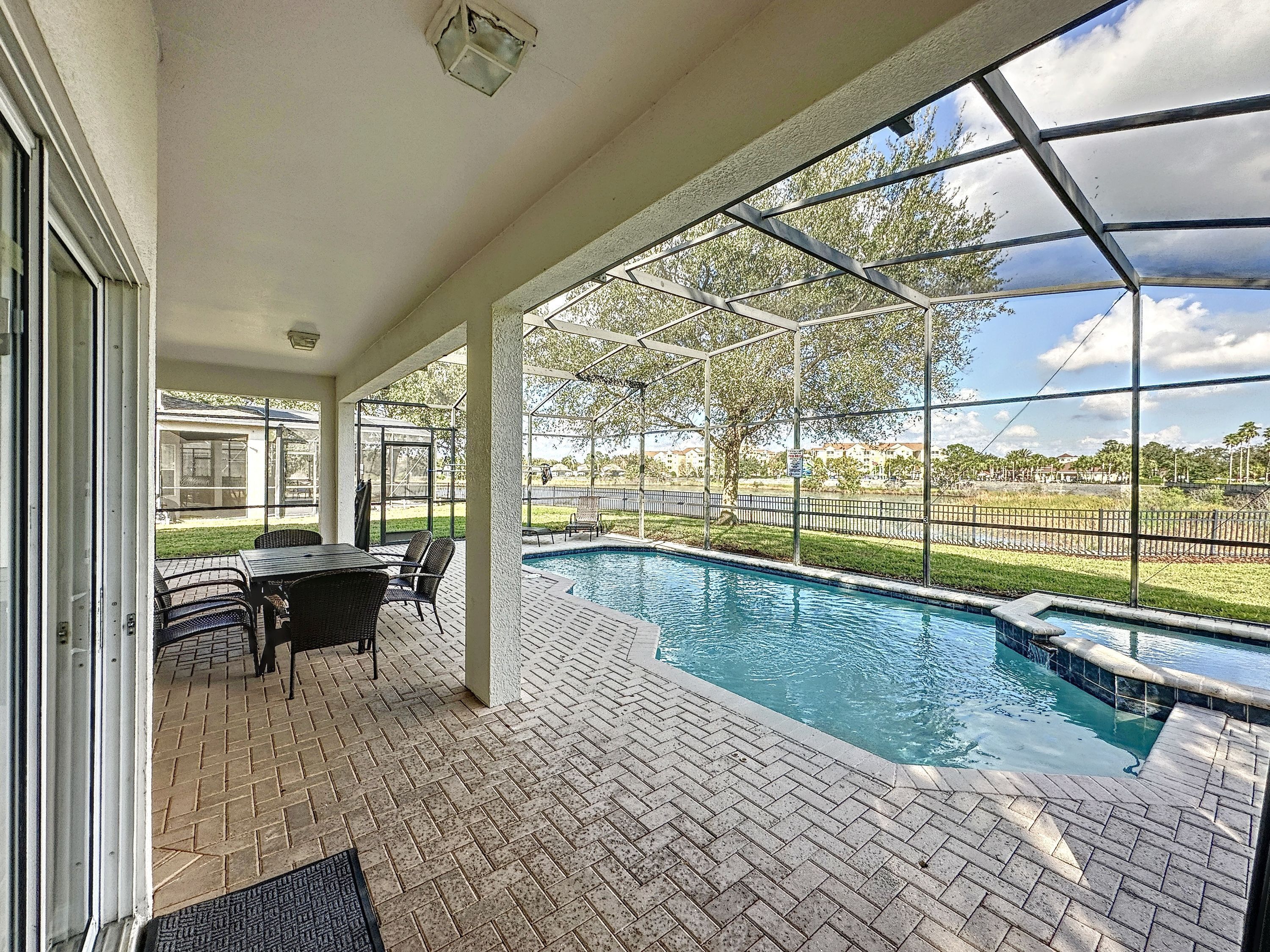 A covered outdoor area with a swimming pool, patio furniture, and a view of the surrounding landscape.