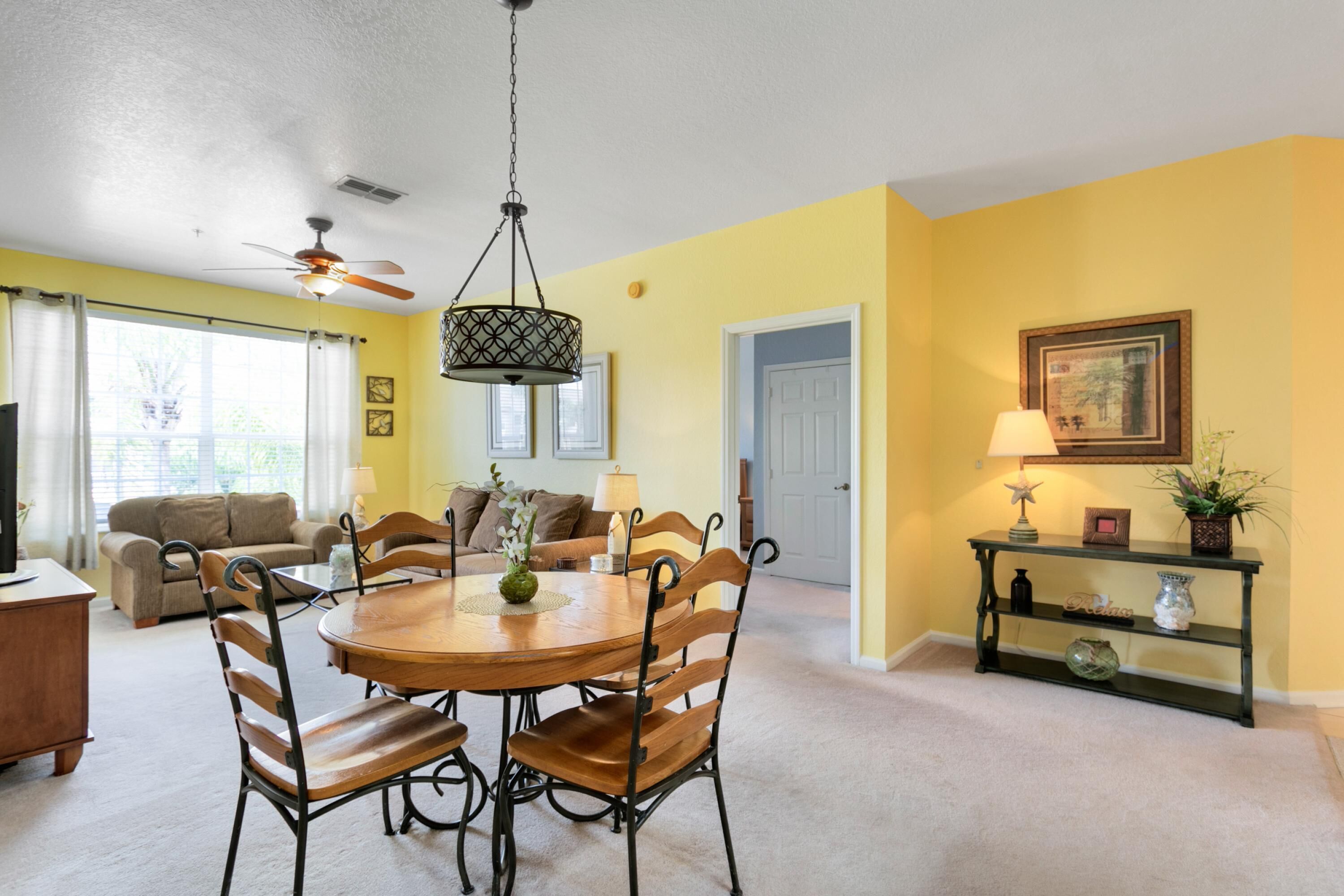 A dining area with a round table and chairs, a ceiling fan, and a console table with decorative items.