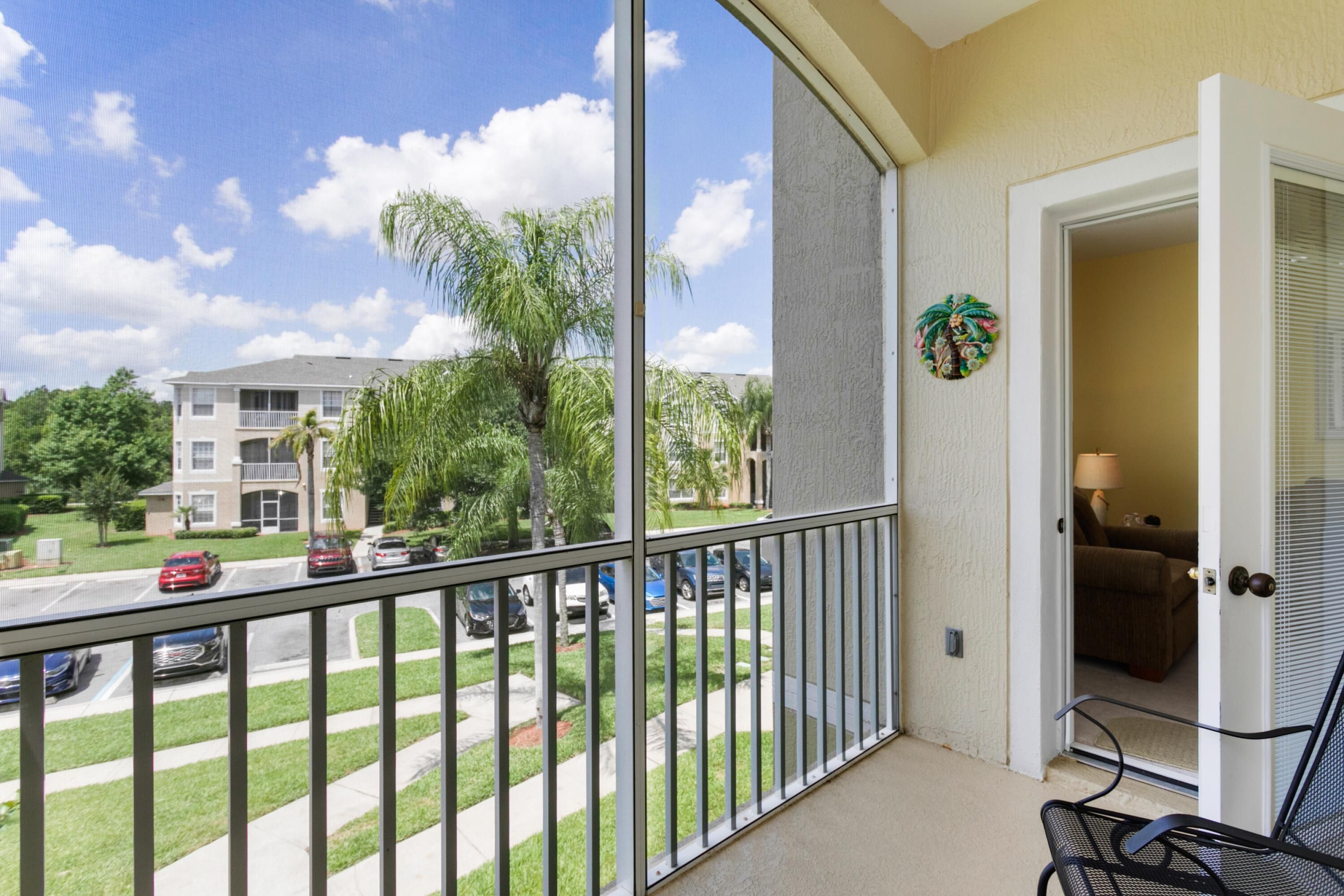 A balcony with a view of a residential street, a door leading to a room, and a small plant decoration.