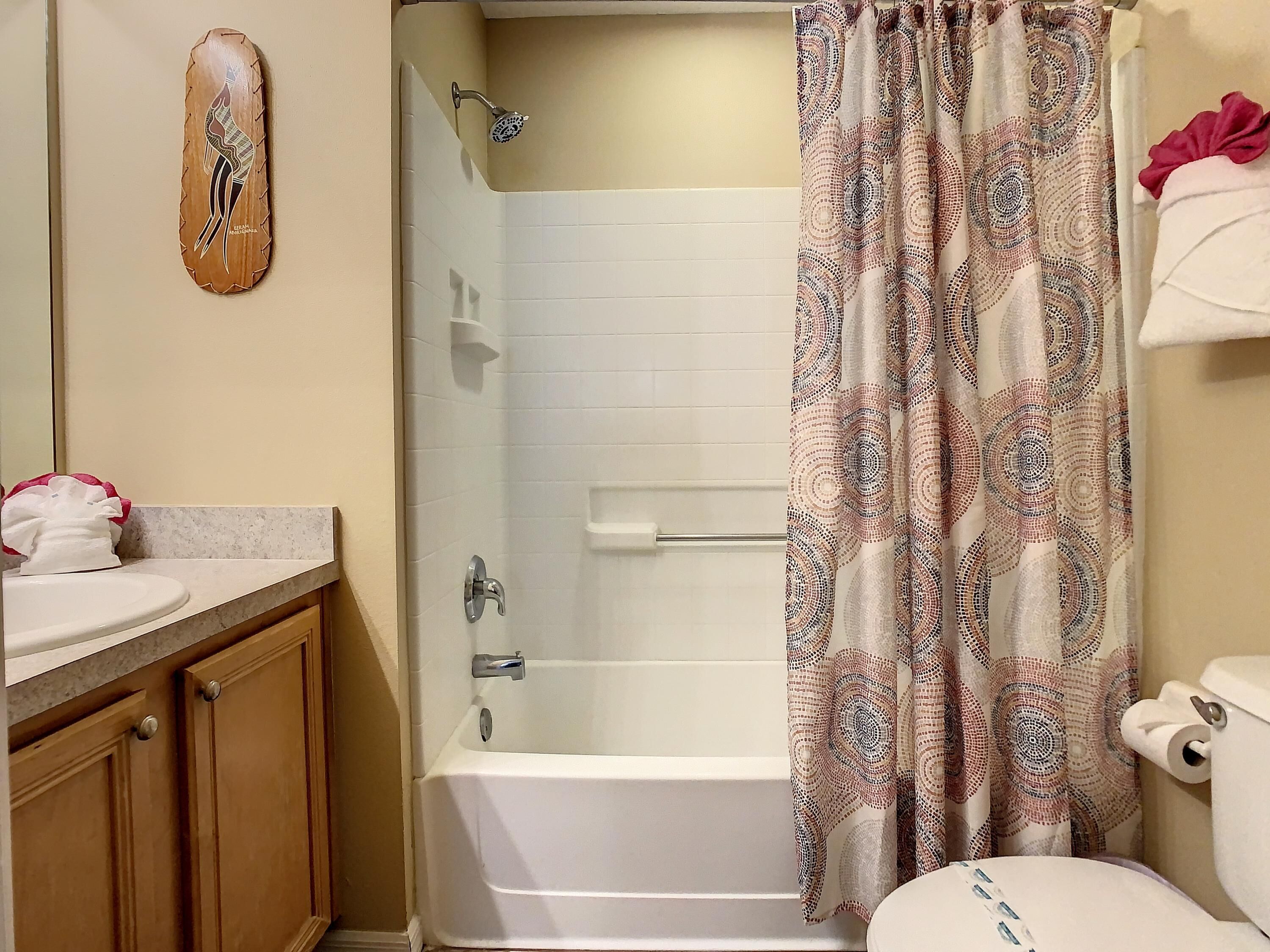 A bathroom with a white bathtub, a shower, a toilet, and a sink.