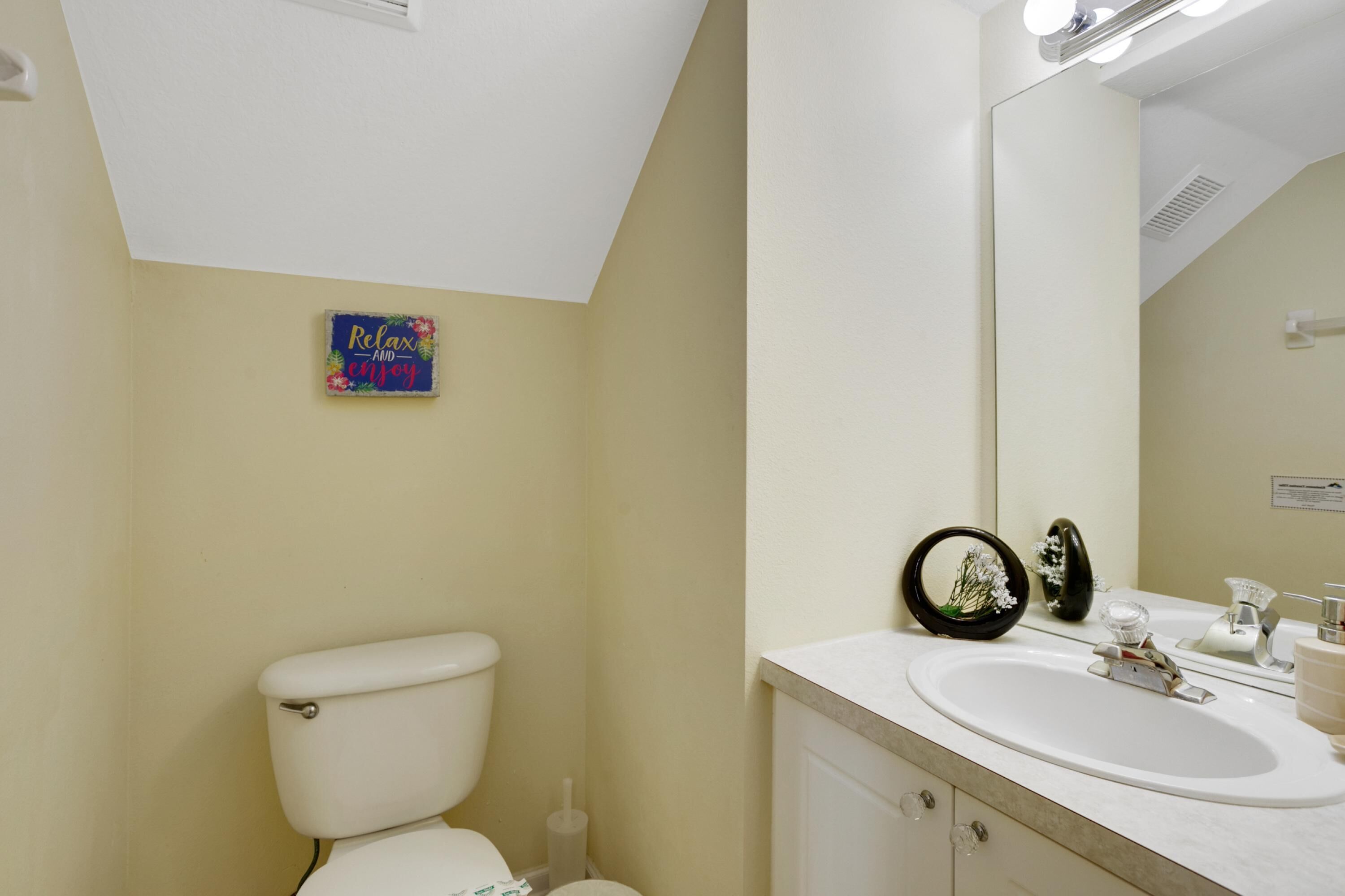 A bathroom with a toilet, sink, and mirror.