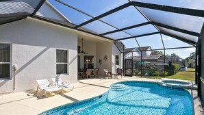 A covered outdoor swimming pool with lounge chairs and a patio area. - Fantastic Resort 5BR House - South Facing Pool Spa (Kissimmee)