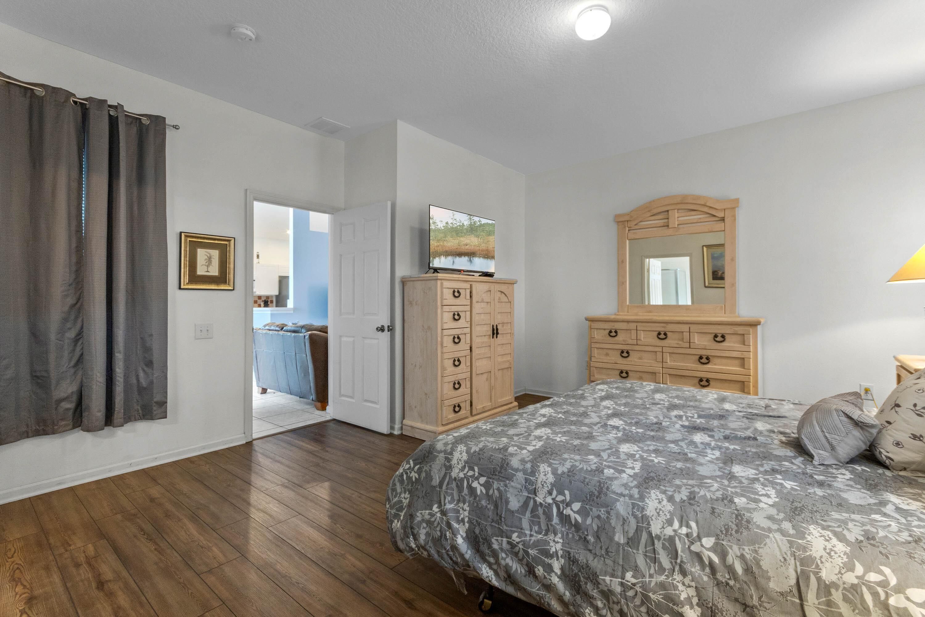 A bedroom with a bed, wooden dresser, and a mirror.